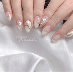 a woman's hands with white and gold manies on their nails, one is holding