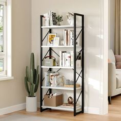 a white book shelf with books on it next to a cactus in a living room