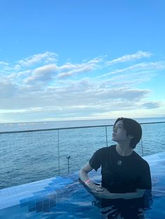 a man sitting in the water on top of a boat looking up at the sky