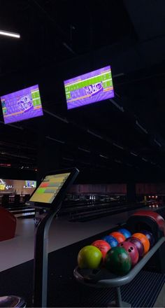 bowling balls are lined up next to each other in a bowling alley with neon signs above them