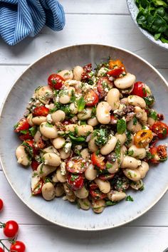 a white bowl filled with beans and tomatoes