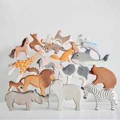 a group of wooden toy animals sitting on top of a white table next to each other