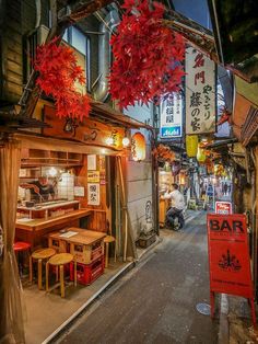 an alley way with tables, chairs and signs on the side walk in front of it