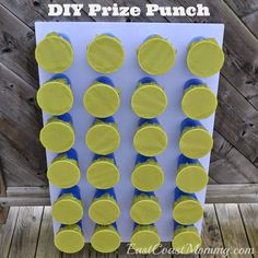 a diy prize punch board with blue and yellow circles on it, next to a wooden fence