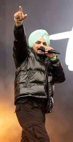 a man with a turban on his head singing into a microphone at a concert