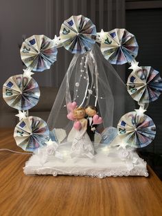 a bride and groom figurine under a wedding arch made out of paper fans