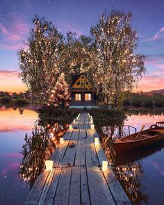 a boat is docked at the end of a dock with lights on it and trees in the background