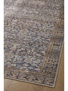 a blue and beige area rug with an intricate design on the bottom, in front of a wooden floor