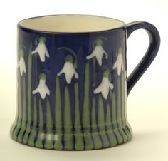 a blue and green mug with white flowers on it