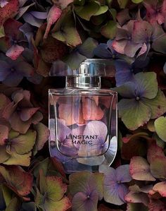 a bottle of perfume surrounded by purple and green leaves with the words instant magic written on it