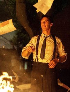 a man standing in front of a fire with papers flying from it's mouth