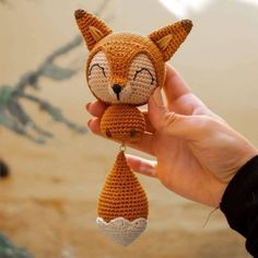 someone is holding up a crocheted stuffed animal that looks like a fox with eyes closed