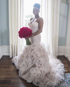 a woman in a wedding dress holding a bouquet of flowers and posing for the camera