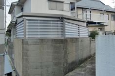 a concrete wall next to a building with windows on the top and bottom floor, in front of an apartment complex