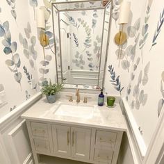 a bathroom with a sink and mirror next to a wallpapered wall behind it