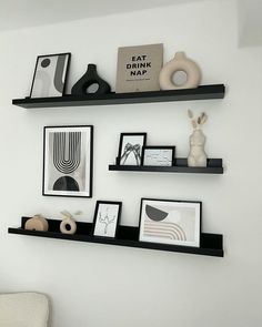 three black shelves with pictures and other items on them in a white walled living room