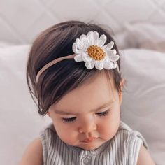 a baby girl wearing a headband with a flower on it