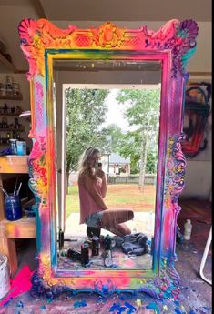 a woman sitting in front of a colorful mirror