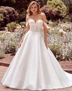 a woman in a white wedding dress posing for the camera with her hands on her hips