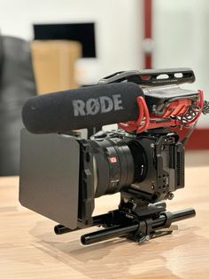 a video camera sitting on top of a wooden table with a microphone attached to it