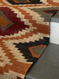 an orange and brown rug sitting on top of a stair case