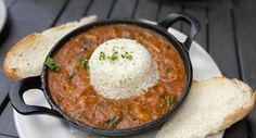 a white plate topped with bread and a bowl filled with chili cheese covered soup on top of it