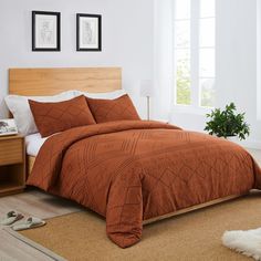 a bed with an orange comforter and two pictures on the wall in front of it