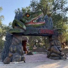 the entrance to an amusement park with a large alligator statue