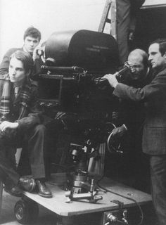 an old black and white photo of men in front of a camera