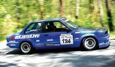 a blue car driving down a road next to trees