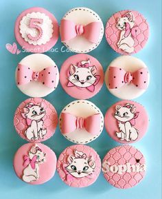 pink and white cupcakes decorated with cartoon cats, bows, and other decorations