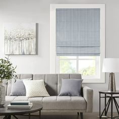 a living room filled with furniture and a window covered in blue roman blind shades on the windowsill