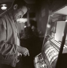 a black and white photo of a man looking at a vending machine in a restaurant