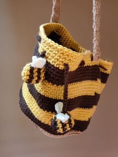 a crocheted yellow and brown purse hanging from a hook on a wall or ceiling