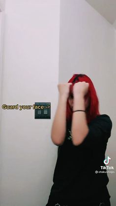 a woman with red hair standing in front of a white wall