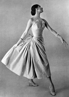 a black and white photo of a woman in a dress with her arms spread out