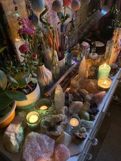 a table topped with lots of different types of candles and flowers on top of it