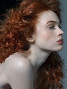 a red haired woman with freckles on her face and shoulder looking to the side