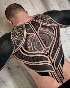 a man's back with an intricate tattoo design on his upper and lower half