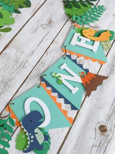 a paper banner that says welcome to new baby on it's first birthday with dinosaurs and leaves