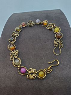 a gold bracelet with multi colored stones on it