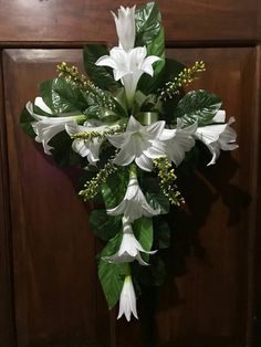 a bouquet of white flowers and greenery hangs on a door handle in front of a wooden paneled wall