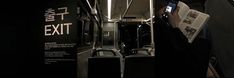 a person reading a book while sitting on a bus with an exit sign in the background