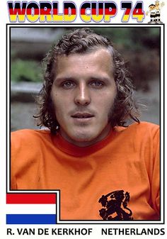 a man with long hair wearing an orange shirt and looking at the camera, in front of a world cup poster