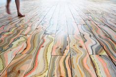 a person walking across a wooden floor covered in multicolored marble