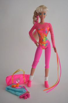 a barbie doll is posed next to a pink handbag and some toys on a white background