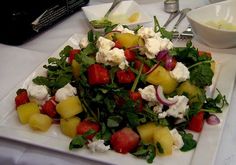 a white plate topped with salad and fruit