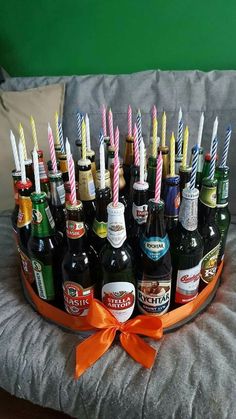 a tray filled with lots of beer bottles on top of a couch next to a pillow