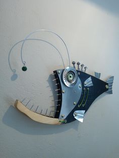 a fish sculpture hanging on the wall next to a string attached to it's side