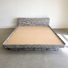 an upholstered bed frame with no headboard and foot board is shown against a white wall